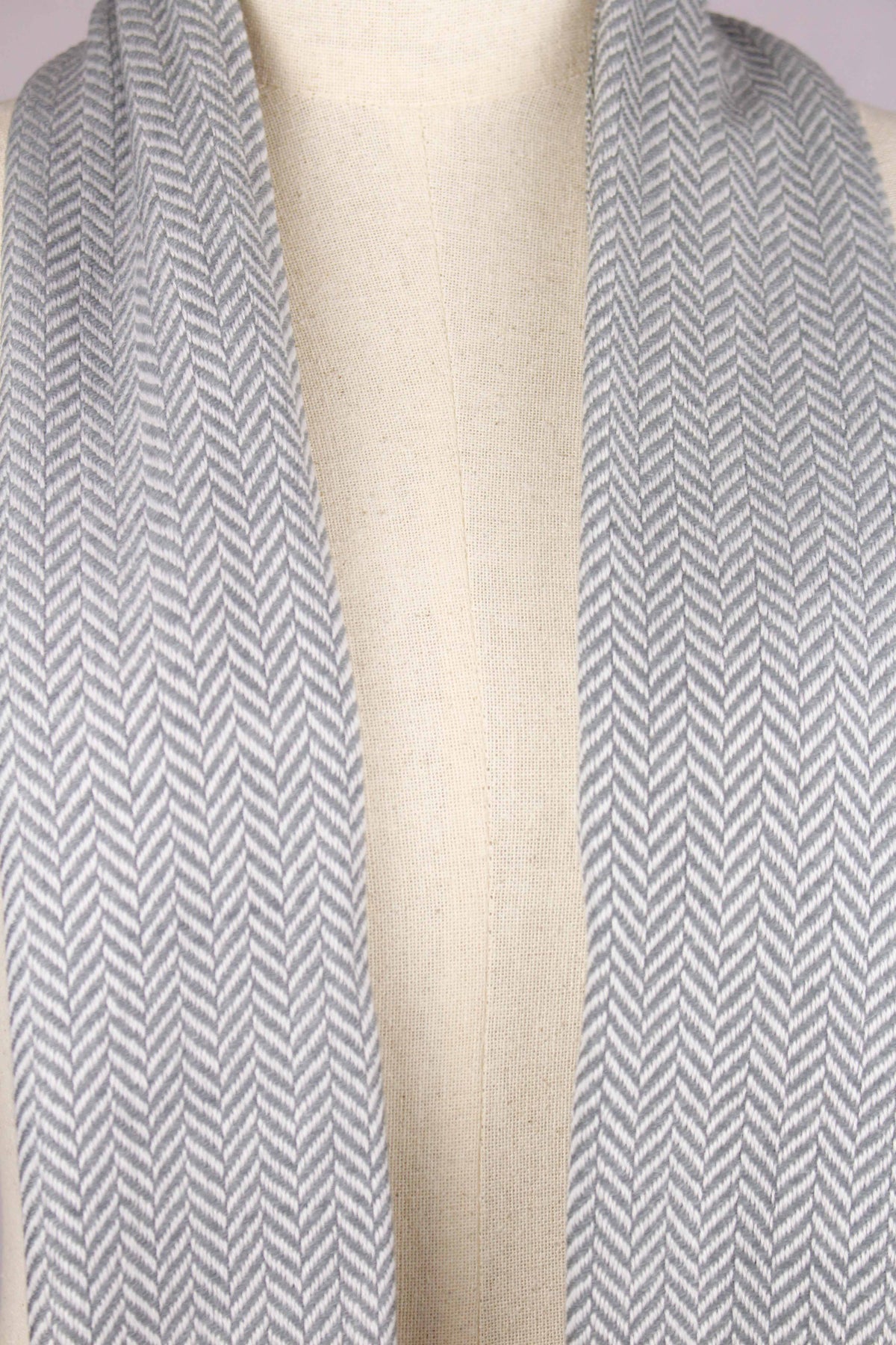 Women's cashmere wool herringbone gray scarf draped around the neck of a mannequin, showing the herringbone weave detail