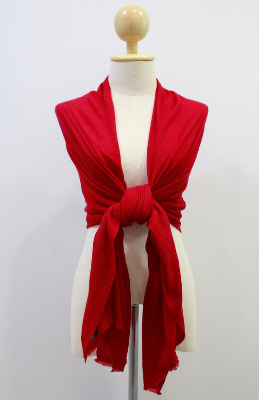 Crimson red cashmere scarf draped over the shoulders and styled with a front knot on a display mannequin against a white background
