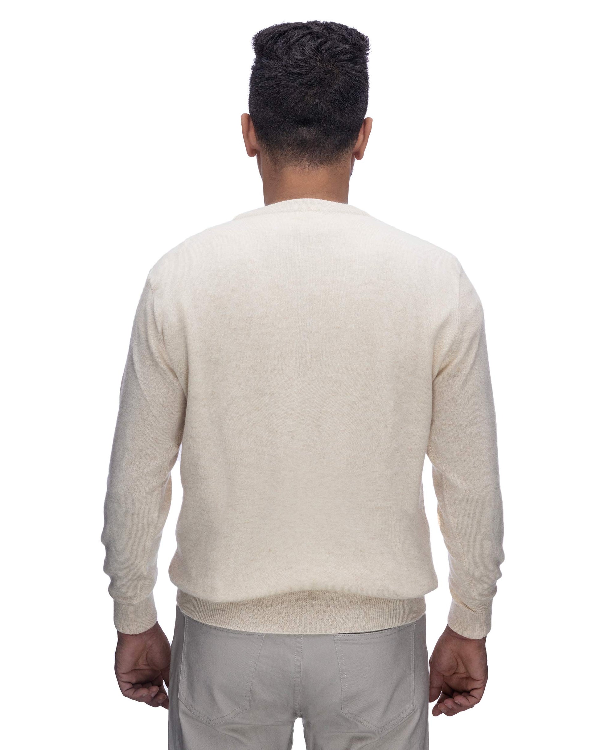 A man viewed from behind wearing a light cream-colored long-sleeve knit sweater and light gray trousers, isolated on a white background.