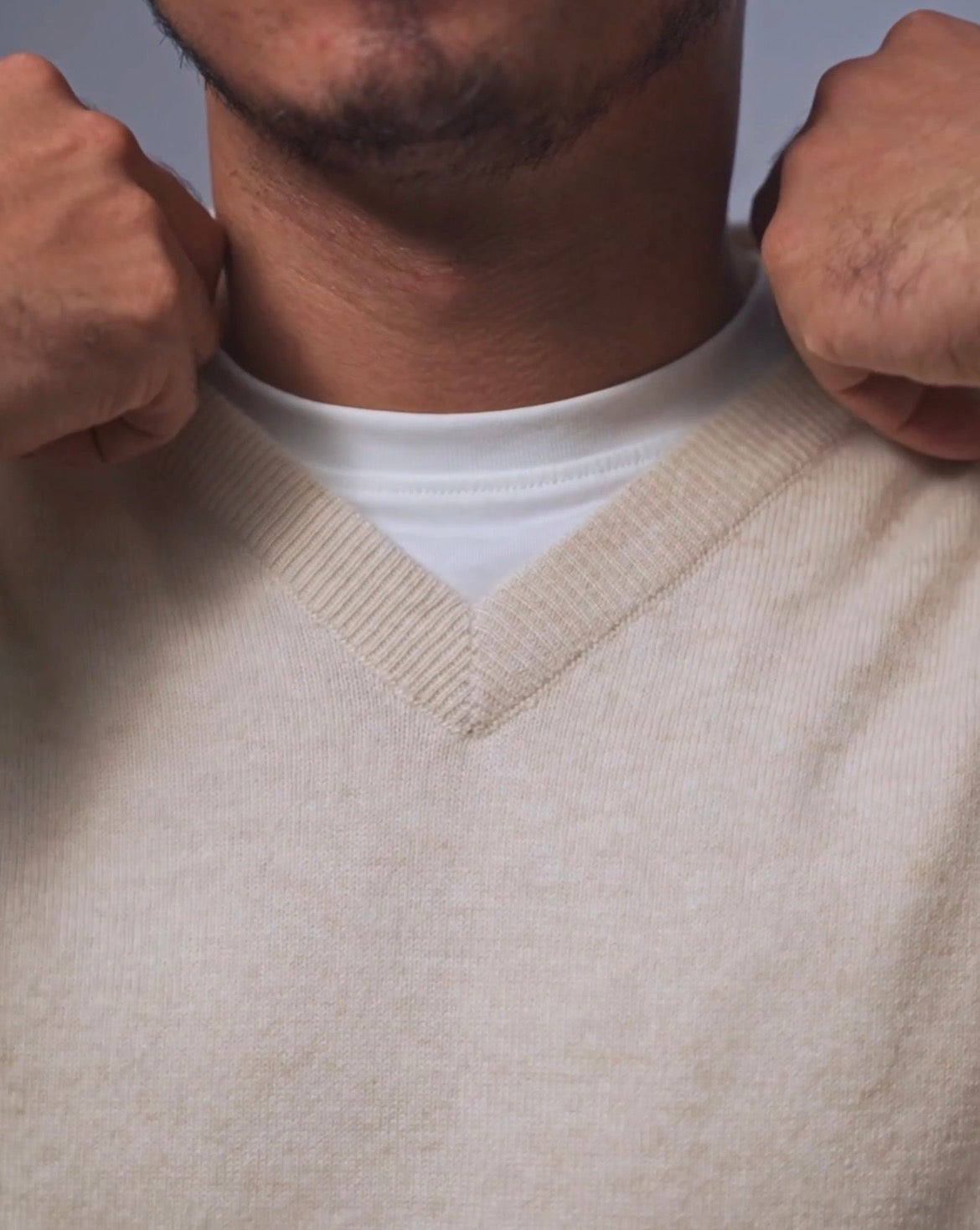 Men's v-neck knit sweater in cream and dark gray variants featuring ribbed neckline detail and classic fit.