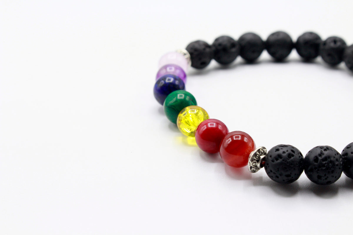 Close-up of a black Lava Stone bracelet showing seven colored chakra stones.