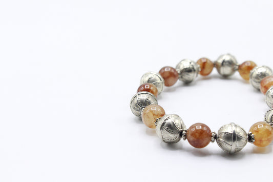 Close-up of polished Red Jade beads and decorative silver-tone metal beads.