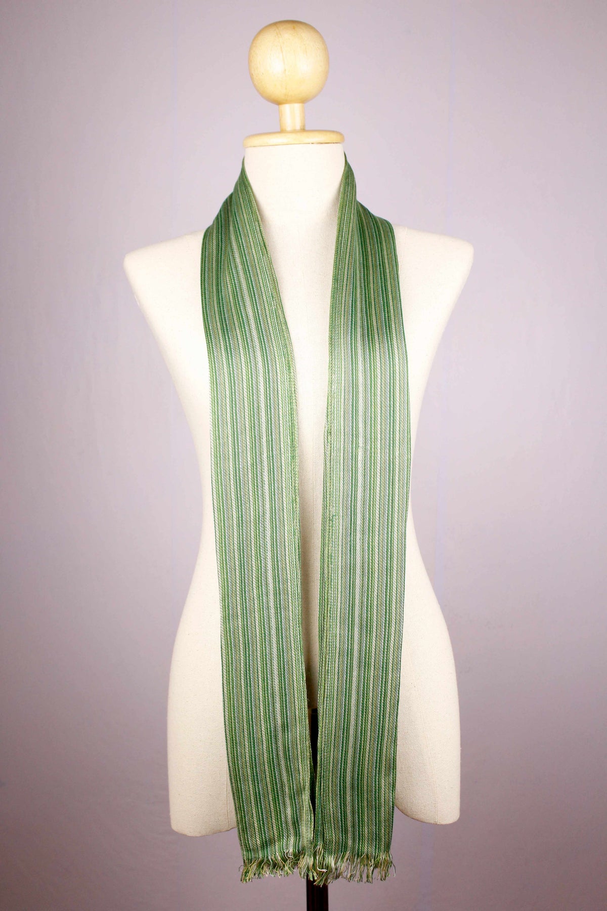 Women's 100% bamboo shades of green striped scarf draped on a mannequin, showing the full length and micro-fringed ends