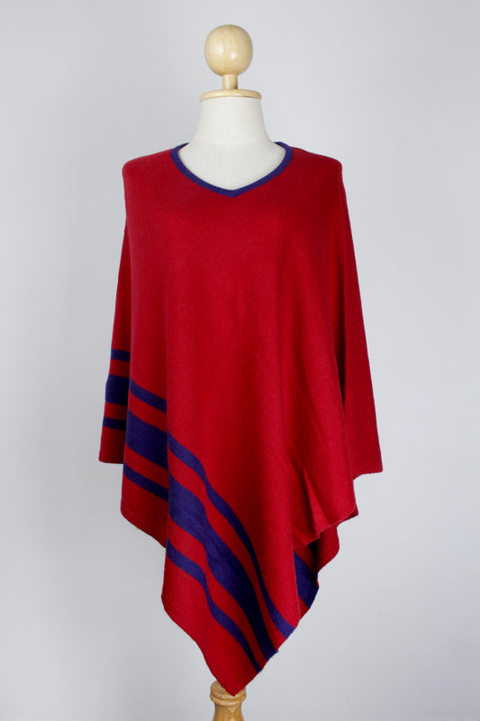Women's red cashmere V-neck poncho with royal blue neckline trim and stripe detailing, front view on a mannequin.