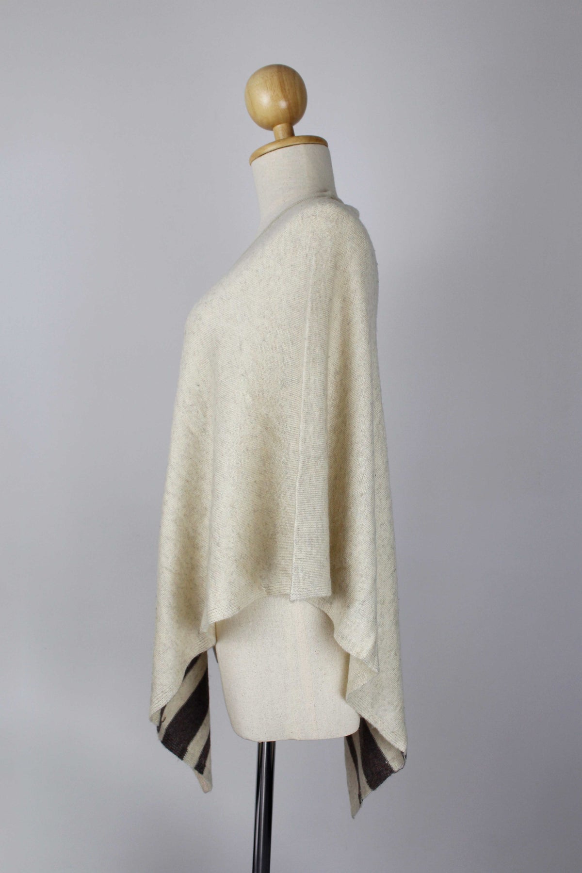 Women's Cream cashmere poncho with Dark Brown stripe detailing displayed on a mannequin, side view.