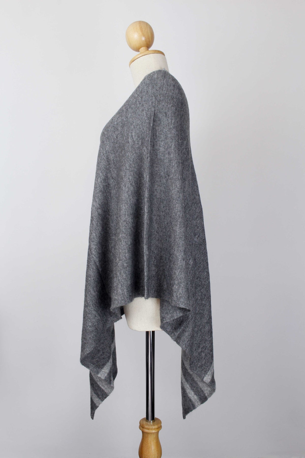 Women's dark gray cashmere poncho with Silver Gray stripe detailing displayed on a mannequin, side view.