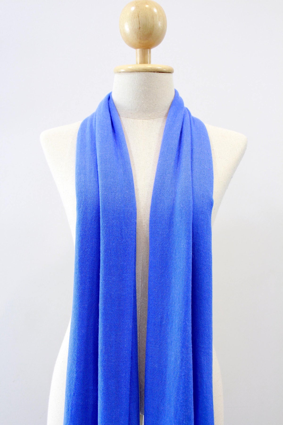 Cornflower Blue cashmere scarf draped around the neck of a mannequin, front view. 