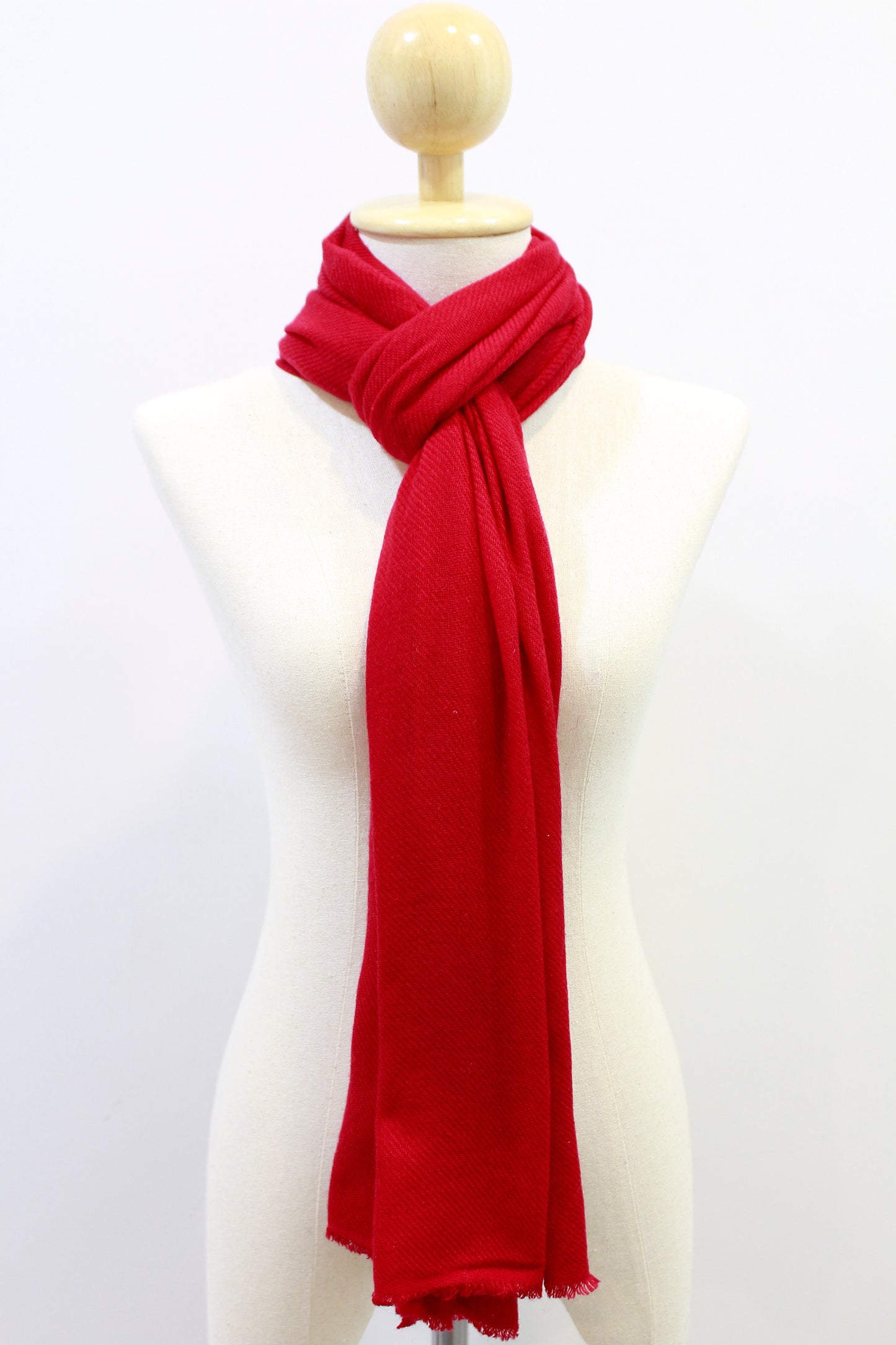 Crimson red cashmere scarf styled in a front-loop neck wrap on a display mannequin against a white background