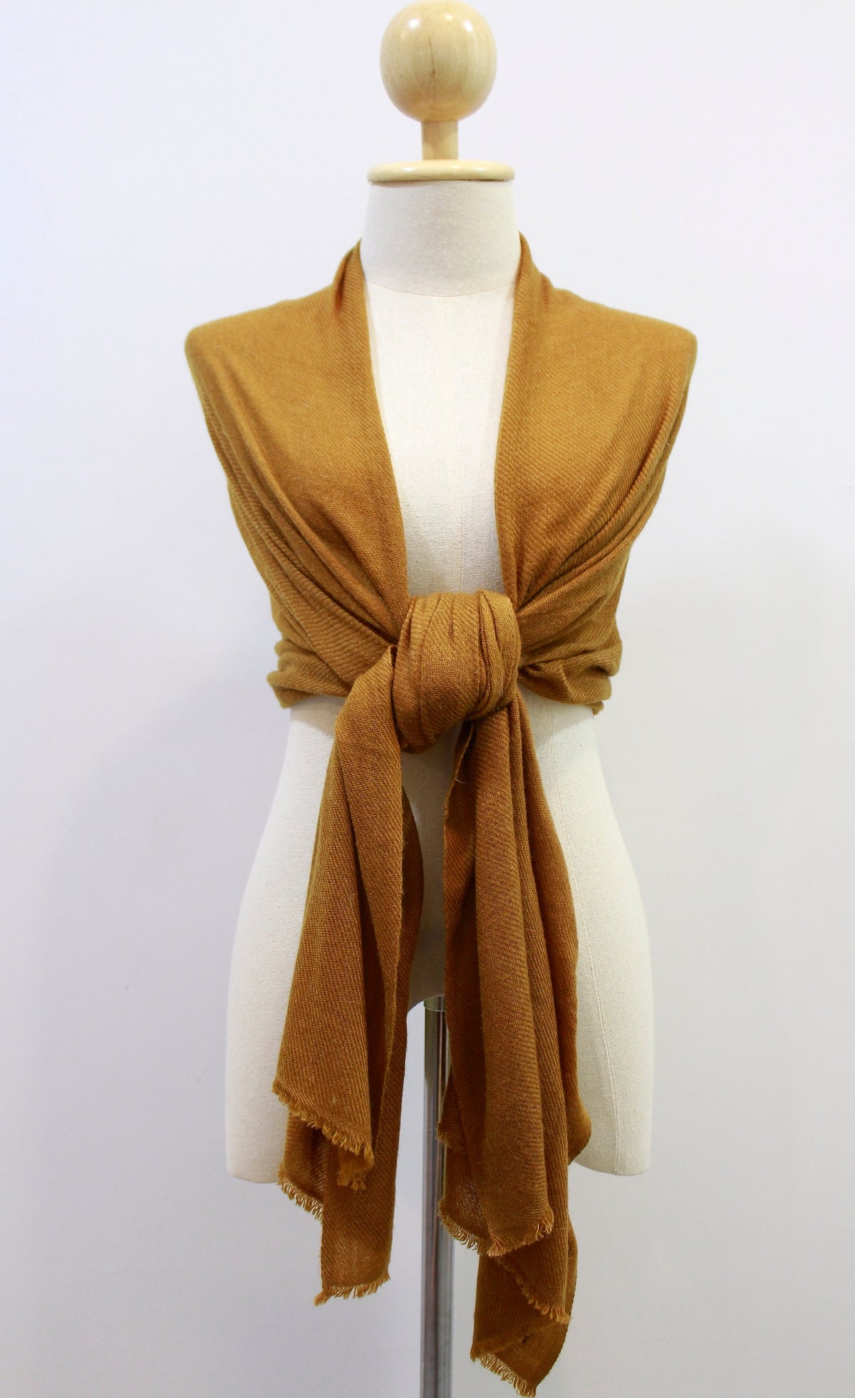 Mustard Yellow cashmere scarf draped over the shoulders and styled with a front knot on a display mannequin 