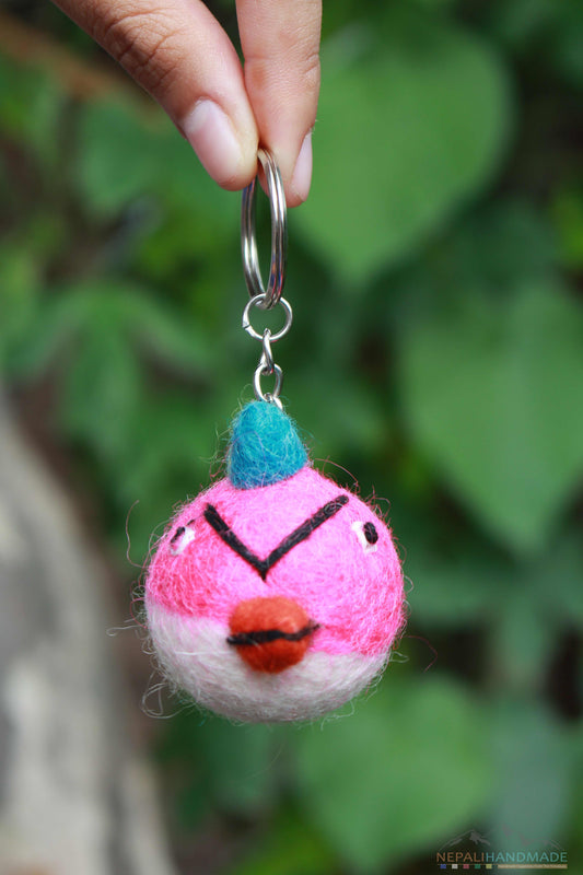 pink and white colored angry bird keychain handmade from felted merino wool, human holding the keychain at the top and hanging it